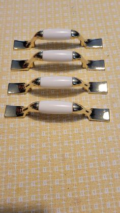 four forks are lined up on a tablecloth with gold and white trimmings