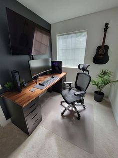 a computer desk with a guitar hanging on the wall next to it and a chair in front of it