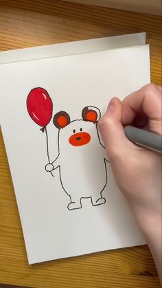 someone is drawing a bear with balloons on the paper and it looks like he's going to fly