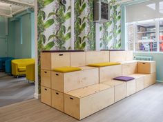 an office with colorful wallpaper and wooden benches in the center, along with brightly colored chairs