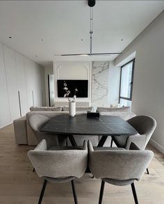 a dining room table with four chairs and a vase on the centerpiece in front of it