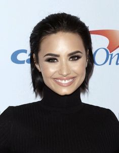 a smiling woman with dark hair wearing a black turtle neck sweater