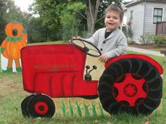 a young boy sitting on top of a red tractor