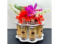 there are three bottles with flowers in them on the tray and one is filled with liquor