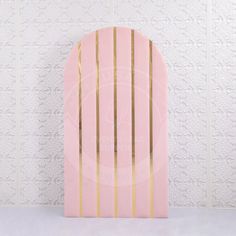 a pink surfboard with gold stripes against a white wall