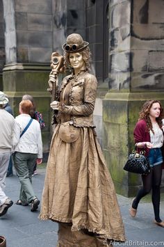 a statue of a woman in a long dress and goggles holding a lamppost