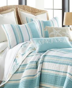 a bed covered in blue and white striped comforter next to a night stand with a lamp on it