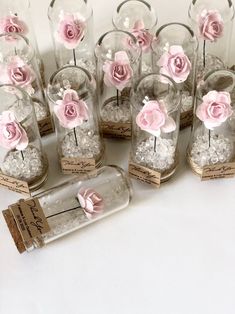 small glass jars filled with pink flowers on top of a table