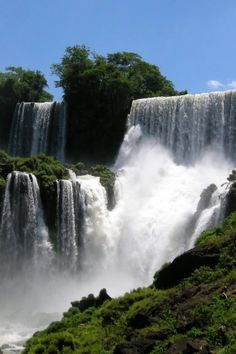 the waterfall is surrounded by lush green trees and water cascading from it's sides