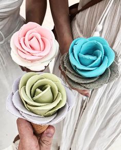 three different colored flowers are held in their hands