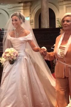 two women in wedding gowns standing next to each other at the alter with their hands together