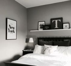 a bed with white sheets and pillows in a bedroom next to two framed pictures on the wall