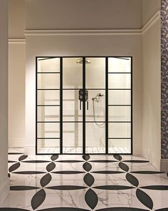 an elegant bathroom with black and white tile flooring, glass doors and chandelier