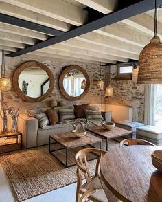 a living room filled with furniture next to a wooden table and two round mirrors on the wall