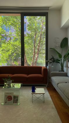 a living room filled with furniture and a large window overlooking the trees in front of it