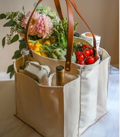 a tote bag filled with groceries sitting on top of a table next to flowers