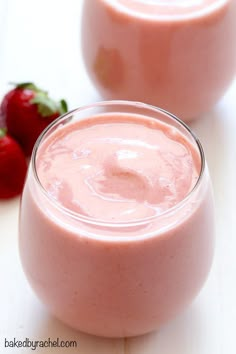 two glasses filled with pink smoothie next to strawberries