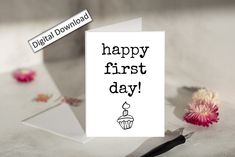 a white card with the words happy first day on it next to a pink flower