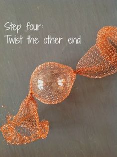 an orange string sculpture with the words step four twist the other end