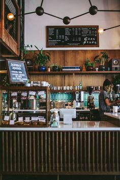 the interior of a coffee shop with lots of counter space and plants on the shelves