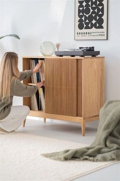 a woman sitting on the floor in front of a record player