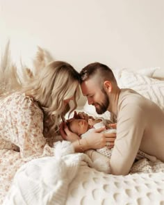 a man and woman laying on top of a bed with a baby in their arms