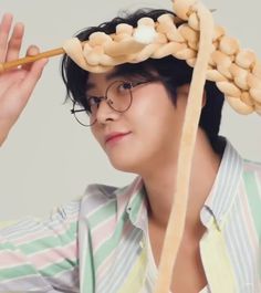 a young man is holding noodles on his head with chopsticks in front of him