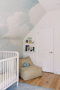 a baby's room with a white crib and blue sky painted on the wall