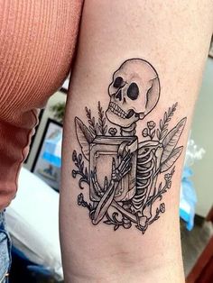 a woman with a tattoo on her arm holding a knife and a skull in it