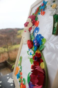 a close up view of a colorful wall decoration with flowers and leaves on the side