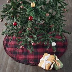 a christmas tree with presents under it on a red and black tableclothed placemat