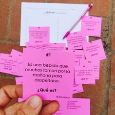 a person holding a pink piece of paper with spanish words on it, surrounded by sticky notes