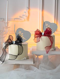 two cakes decorated with bows and hearts on top of each other, sitting on white trays