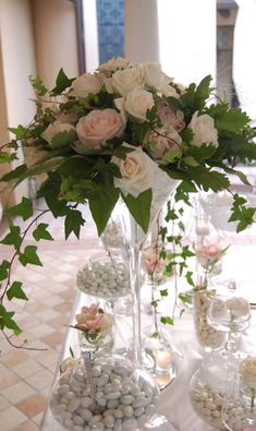 a vase filled with flowers and rocks on top of a table covered in greenery