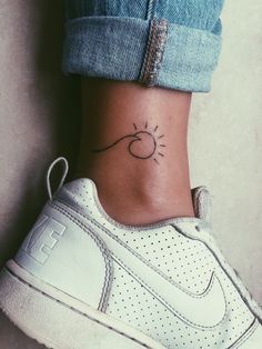 a woman's foot with a small sun tattoo on her left side ribcage