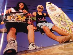 two people sitting on a ledge with skateboards in their hands and one person holding a skateboard