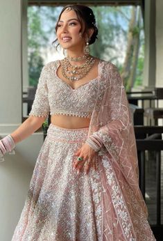 a woman in a pink and white lehenga is posing for the camera with her hand on her hip