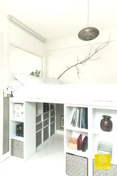 a white loft bed sitting under a window next to a book shelf filled with books