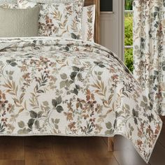 a bed covered in a white and brown floral comforter set with matching pillow cases