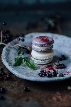 a plate with some food on it next to blackberries and berries, one is covered in powdered sugar