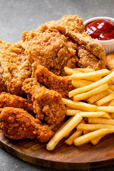 fried chicken, french fries and ketchup on a wooden plate