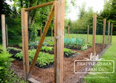 a garden with lots of plants growing in the ground and fenced off to the side