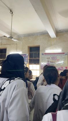 a group of people standing in front of a classroom with posters on the wall behind them