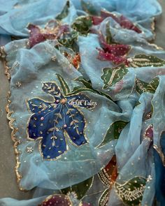 blue and gold embroidered fabric with flowers on the bottom, sitting on top of a table