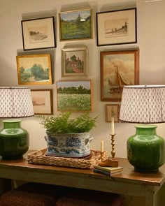 two green vases sitting on top of a wooden table next to lamps and pictures