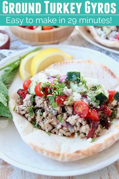 a pita filled with meat and vegetables on top of a white plate next to lemon wedges