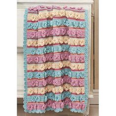 a crocheted blanket hanging on the side of a dresser