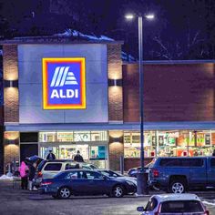 an aldi store at night with cars parked in the parking lot and people standing outside