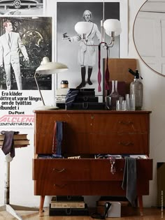 an old dresser is filled with clothes and other items in front of a wall mounted poster