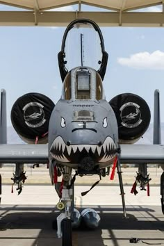 an airplane with a shark face painted on it's nose and the cockpit door open